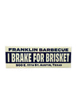 Dark blue and beige bumper sticker that says in big letters: I BRAKE FOR BRISKET". Across the top of the sticker in medium sized letters it says: "Franklin Barbecue". Across the bottom of the sticker in smaller font is our address: "900 E. 11th St. Austin, Texas".