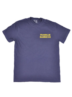 Front of navy blue t-shirt. "Franklin Barbecue" is printed in yellow on the top left side of the shirt. 