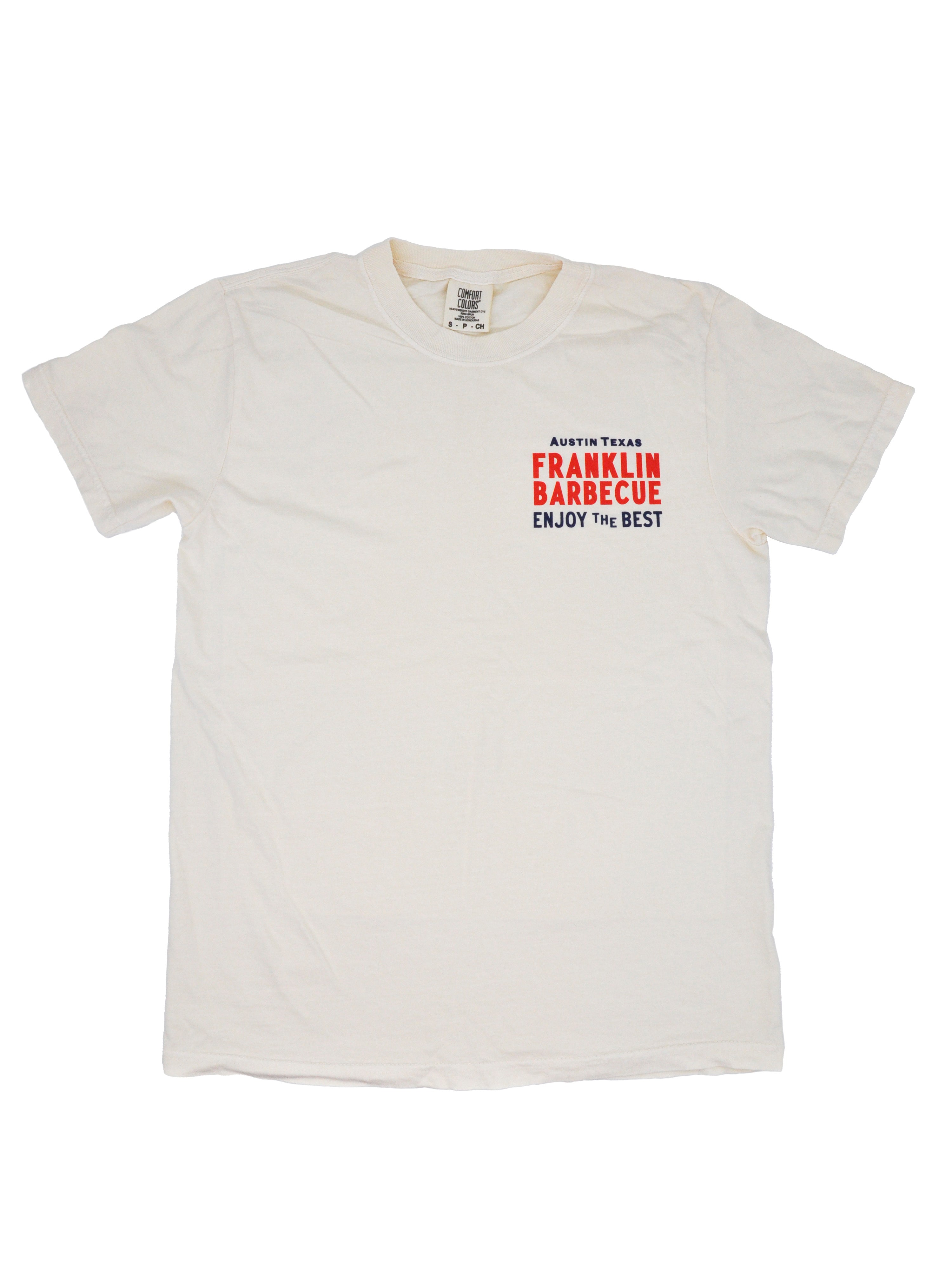 Front side of a cream t-shirt. On the shirt's top left it says in blue and red letters "Austin, TX. Franklin Barbecue. Enjoy the best."