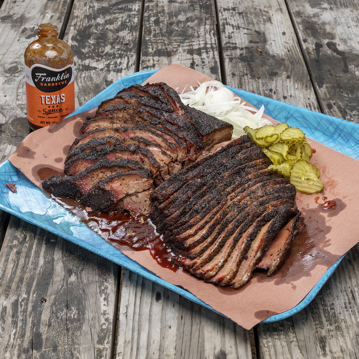 Large barbecue spread displayed atop large serving tray beside an open bottle of Franklin Original Barbecue Sauce