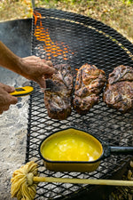 Meat cooking on a grill. A man checks the meat with a thermometer. 