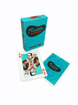 Turquoise playing card box with Franklin Barbecue logo in black and orange on front and black checkers on the side. In front of box, 2 cards are displayed showing Aaron Franklin as the King of Hearts card and the other card is displaying the back of card which is a blue swirl pattern with the Franklin Barbecue logo