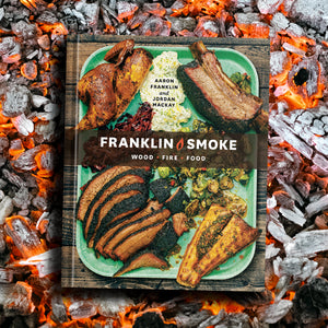 Cover of the Franklin Smoke book laid upon a bed of flaming coals. 