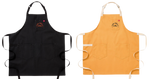 A black apron next to a yellow apron. Both feature two big pockets at the bottom.  Both have a smaller breast pocket on the left side of the apron. On the breast pocket it says "You Grill Girl. Aus Tex". The text is orange on the black apron and black on the yellow apron.