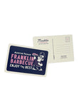 Dark blue postcard with thick white border. The postcard reads "Austin Texas. Franklin Barbecue. Enjoy the Best". The words "Franklin Barbecue" are in pink letters. To the right of the words is a cartoon of Aaron Franklin holding up a tray of meat. We also see the back of the postcard. Franklin's 900 E. 11th St address is listed as the return address. On the top right is a place to put a stamp. On the right side of the card is five lines to write a message.