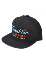 Alternate angle of Black cap with Franklin Barbecue text logo in blue and orange. Below that is Austin Texas in white.