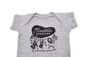 Heather Grey onesie with Franklin Barbecue bean Logo in black and logo of dancing family holding the letters B-B-Q while wearing pig-nose masks also in black. Below the dancing family is the address of Franklin Barbecue also in black.