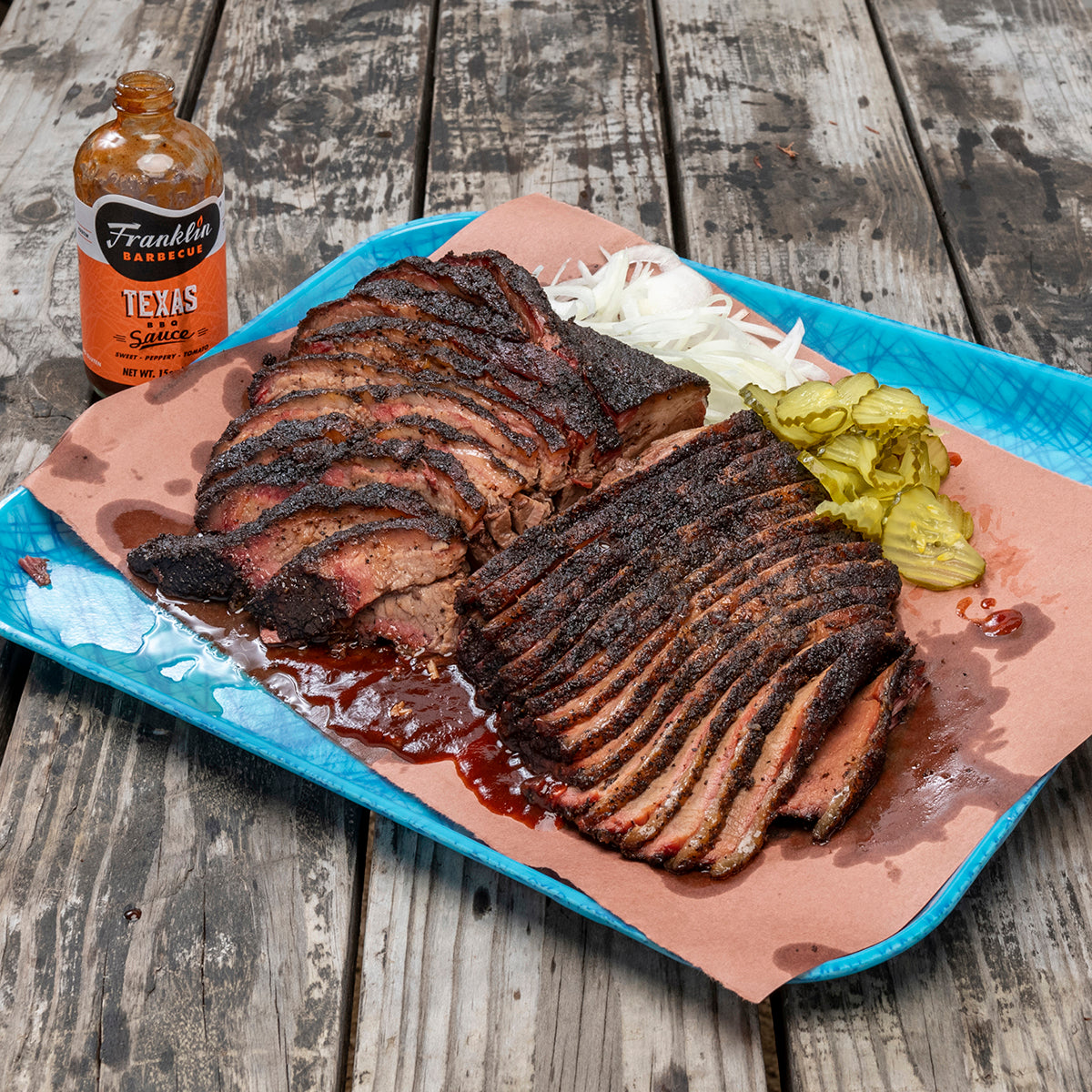 Large Franklin Barbecue serving tray filled with cut brisket covered in sauce, onions and pickles