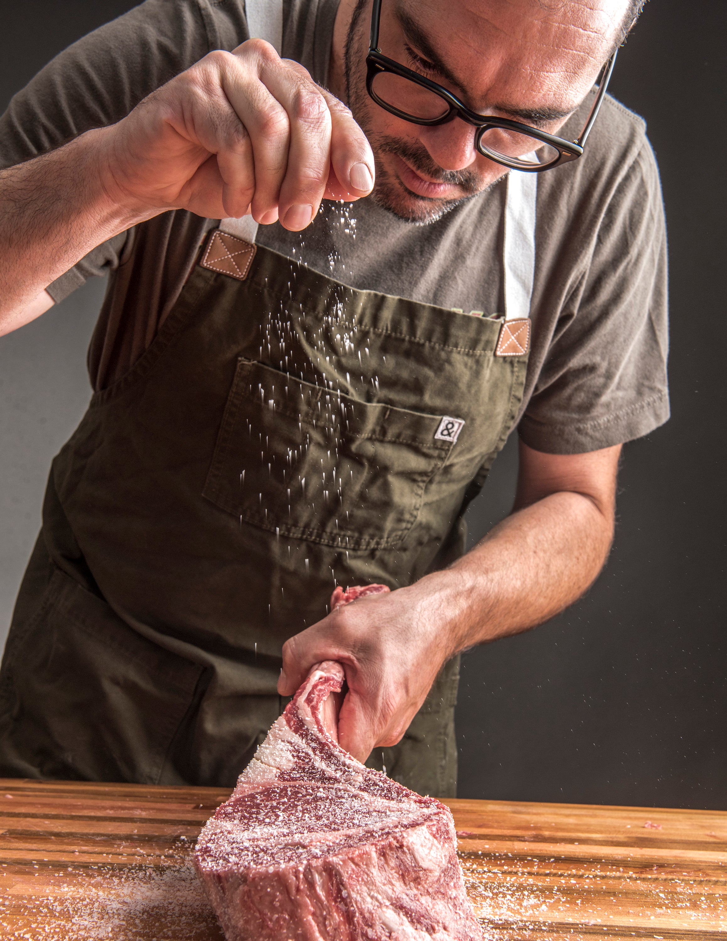 Picture from Franklin Steak book. Aaron Franklin sprinkling salt on steak.