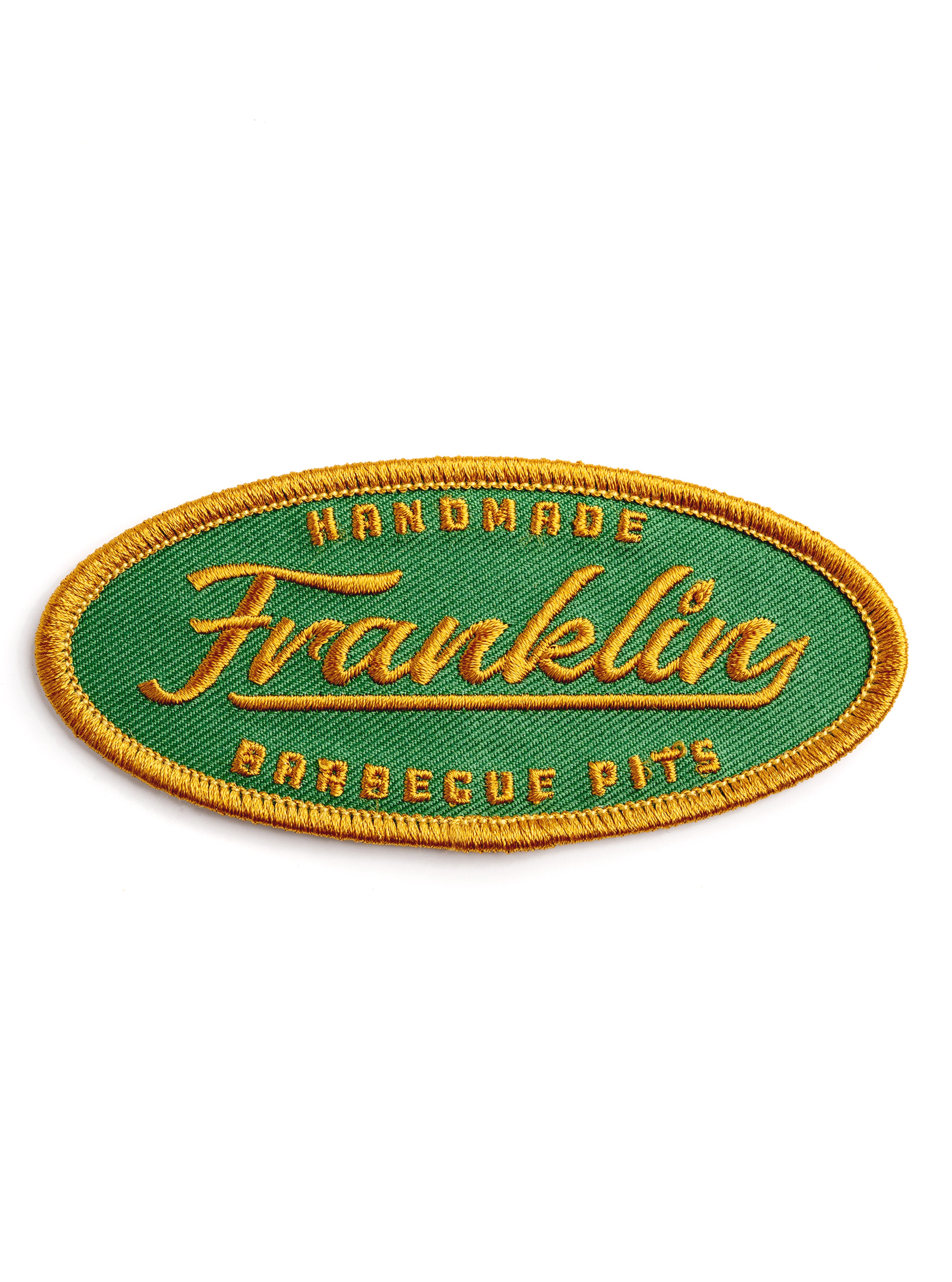 Oval patch with green background and stictched logo saying "Handmade Franklin Barbecue Pits" in gold and bordered in gold