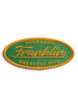 Oval patch with green background and stictched logo saying "Handmade Franklin Barbecue Pits" in gold and bordered in gold
