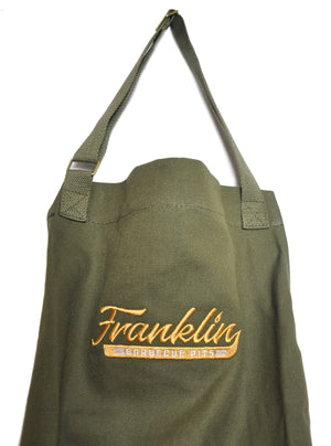 Close up on Green apron with stitched on Franklin Barbecue logo in gold 
