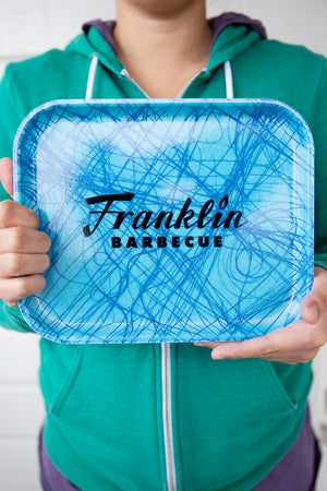 Model holding the small Franklin Barbecue Cafeteria tray face out.