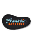 Black patch shaped like Franklin Barbecue bean logo with blue and orange lettering