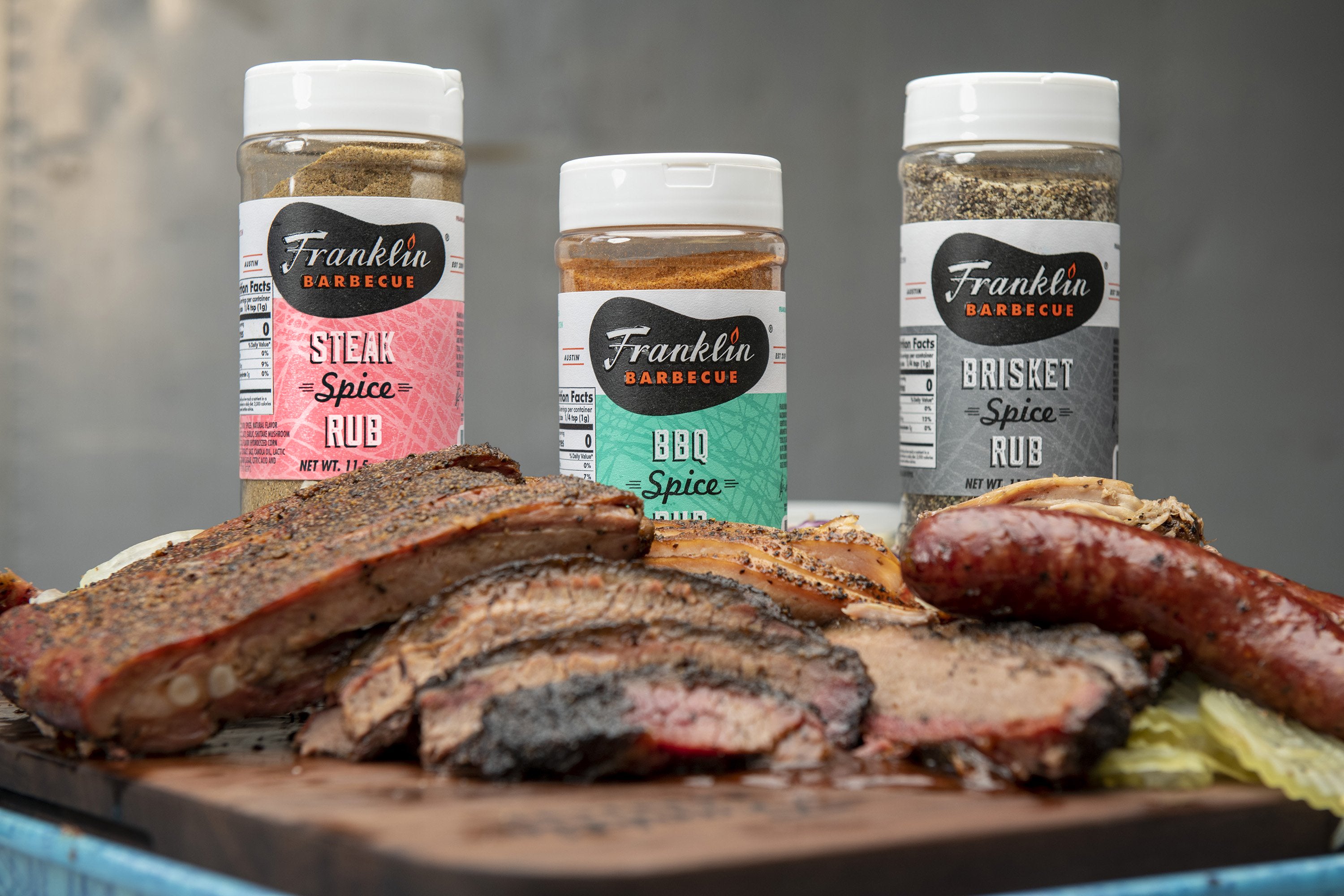 All three spice rubs displayed behind a large platter of barbecue.