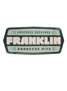 Rectangular aluminum tacker sign with "Franklin handmade backyard barbecue pits" printed in forrest green, light green, and cream.