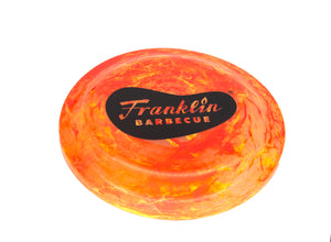 Orange-swirl Franklin Frisbee with screen printed logo of Franklin Barbecue bean in black
