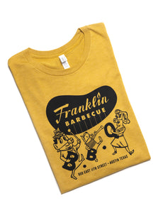 Heather yellow t-shirt with Franklin Barbecue bean Logo in black and illustration of dancing family holding the letters B-B-Q while wearing pig-nose masks also in black. Below the dancing family is the address of Franklin Barbecue also in black.